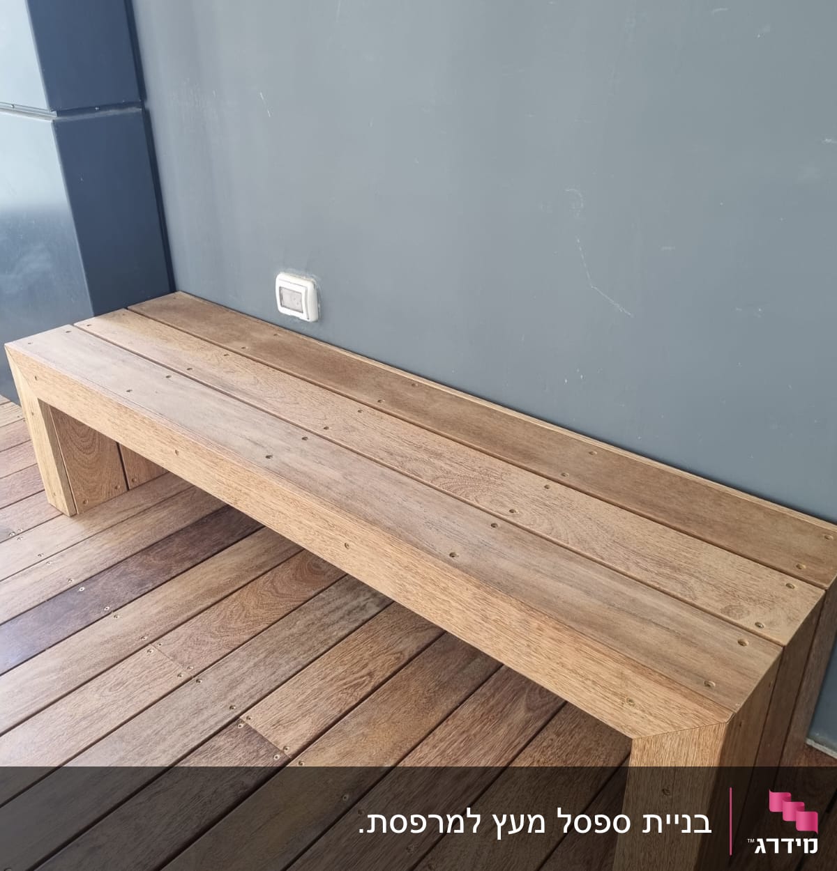 ספסל עץ על רצפת דק ליד קיר אפור